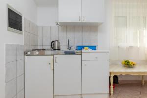 a white kitchen with white cabinets and a sink at Apartments with parking space Omis - 2745 in Omiš +18 photos