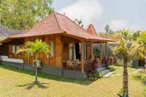 ein kleines Holzhaus in einem Hof mit einer Palme in der Unterkunft Sangat Indah Wooden House Uluwatu in Uluwatu