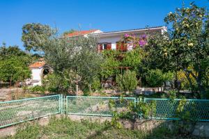 une maison avec une clôture en face d'un jardin dans l'établissement Apartments by the sea Seget Vranjica, Trogir - 1038, à Seget Vranjica