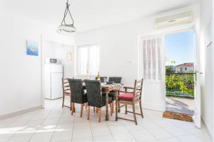 a dining room with a table and chairs and a window at Apartments by the sea Seget Vranjica, Trogir - 1038 in Seget Vranjica