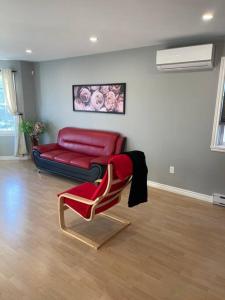 a living room with a red couch and a chair at Armdale Urban Lodge, Dine & Stay in Halifax