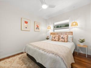 a white bedroom with a large bed and a window at Lazy Days Penthouse - Opposite Shaws Bay - 180 Waterfront Views in East Ballina