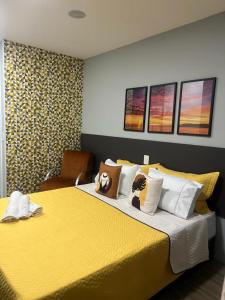 a bedroom with a yellow bed with two stuffed animals on it at Novo Studio Coral Metrô Belém com Piscina in Sao Paulo