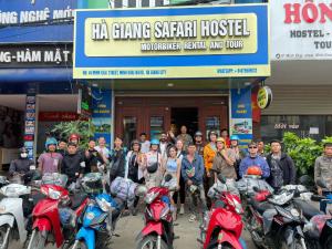 grupa ludzi stojących przed budynkiem z motocyklami w obiekcie Ha Giang Safari Hostel & Motorbikes w mieście Hà Giang