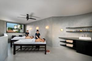 two men are laying on beds in a bathroom at Je Ne Sais Quoi Seminyak in Seminyak