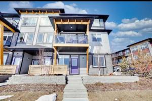 a large white house with a purple door at Comfy 2BR condo in Seton, Southeast Calgary in Calgary