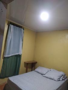 a small bedroom with a bed and a window at Casa de playa de Solano in Transito