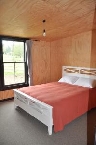 Renagour Cottage - Farmstay with Hot Tub! في وانغانوي: غرفة نوم بسرير كبير في غرفة مع نافذة