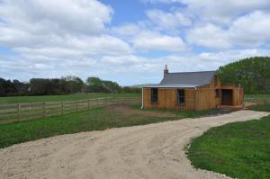 um pequeno edifício numa estrada de terra batida num campo em Renagour Cottage - Farmstay with Hot Tub! em Whanganui