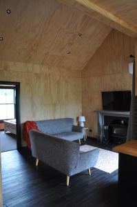 a living room with a couch and a tv at Renagour Cottage - Farmstay with Hot Tub! in Whanganui