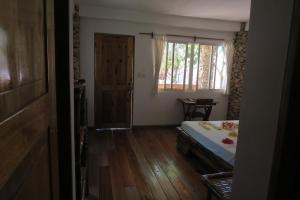 a bedroom with a bed and a window and wooden floors at Tepanee Beach Resort in Malapascua Island
