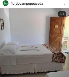 um quarto com uma cama grande e uma porta de madeira em Pousada Flor do Campo em Icapuí