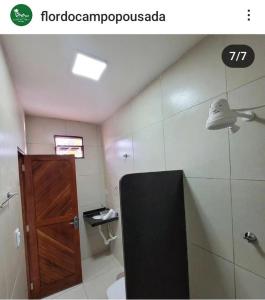 uma casa de banho com um WC e uma porta de madeira em Pousada Flor do Campo em Icapuí