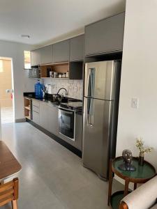 une cuisine avec un réfrigérateur en acier inoxydable et une table dans l'établissement Lindo apto em condomínio top, à Vitória da Conquista