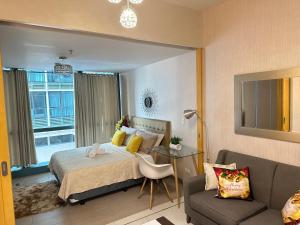 ein Schlafzimmer mit einem Bett, einem Stuhl und einem Sofa in der Unterkunft A Residence with a Mall and a Nightlife @Uptown, BGC in Manila