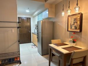 eine Küche mit einem Tisch und einem Kühlschrank aus Edelstahl in der Unterkunft A Residence with a Mall and a Nightlife @Uptown, BGC in Manila
