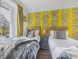 two beds in a room with yellow wallpaper at Pooley Bridge Apartment - Uk44955 in Pooley Bridge