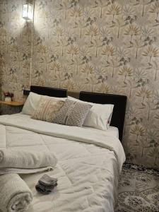 Le Melur في جورج تاون: غرفة نوم مع سرير أبيض وورق جدران مزهر