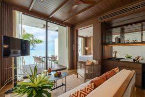 a living room with a couch and a view of the ocean at Cape Fahn Hotel - Private Islands Samui in Choeng Mon Beach +131 photos