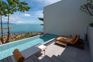 una piscina con mesa y sillas y el océano en Cape Fahn Hotel Samui, en Choeng Mon Beach