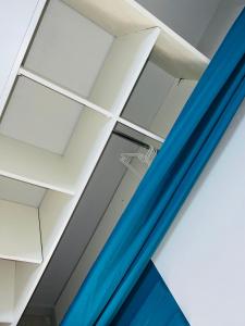 フォール・ド・フランスにあるBelle vueの白い天井と青いカーテンが特徴の客室です。