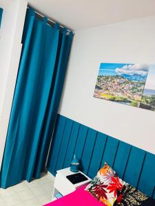 Belle vue في فورت-دو-فرانس: غرفة نوم مع ستائر زرقاء وسرير وصورة