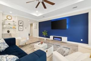 a living room with a blue wall with a tv at Laguna Beach House with a Game Room in Panama City Beach
