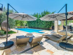 un patio con 2 sombrillas y una piscina en Villa in a typical Istrian rustical style, en Sveti Lovreč Pazenatički