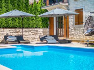 una piscina con 2 sombrillas y sillas junto a una piscina en Villa in a typical Istrian rustical style, en Sveti Lovreč Pazenatički