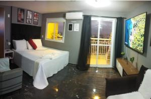 a hotel room with a bed and a balcony at Terraço Harmony Flats GRU in Guarulhos