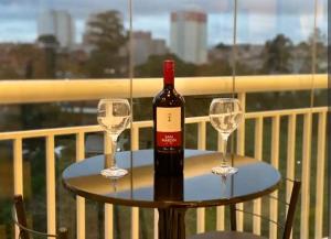 a bottle of wine on a table with two wine glasses at Terraço Harmony Flats GRU in Guarulhos