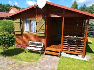 a wooden cabin with a bench in front of it at Holiday cottages for 4 people, Rusinowo in Rusinowo