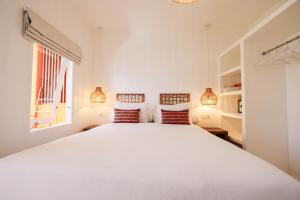a white bedroom with a large white bed with two pillows at The Room Padang-Padang in Uluwatu