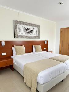 a bedroom with two beds and a picture on the wall at Europeia Hotel in Caldas da Rainha