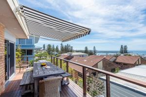 a wooden table on the balcony of a house at Bimbajong Yamba - oceanstays in Yamba