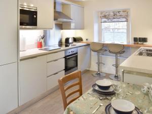 una cocina con armarios blancos y una mesa con sillas. en Hunters Cottage - Uk44956 en Pooley Bridge