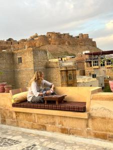 a woman sitting on a bench in front of a castle at kings villa Jaisalmer in Jaisalmer