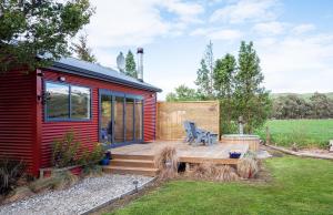 a red tiny house with a wooden deck at Honey Cottage in Ettrick in Millers Flat