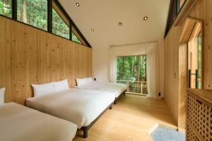 Duas camas num quarto com paredes e janelas de madeira em 自然人村 em Akiruno