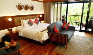 Habitación de hotel con cama y silla en WelcomHeritage Ayatana, Ooty, en Ooty