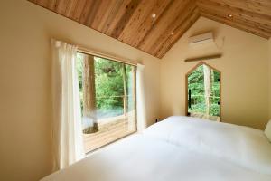 a bedroom with a bed and a large window at 自然人村 in Akiruno