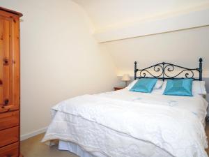 a bedroom with a white bed with blue pillows at Arthfan in Llanelltyd