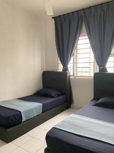 a bedroom with two beds and a window with curtains at ABSYAR HOMESTAY SELASIH in Putrajaya