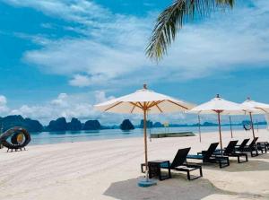 un grupo de sillas y sombrillas en una playa en Royal Beach Villa Sonasea Vân Đồn Quảng Ninh 