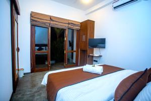 a bedroom with a large bed and a television at The Shades Galle in Galle