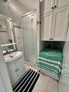 a white bathroom with a shower and a sink at Charming Apartment direct access beach Blankenberge in Blankenberge