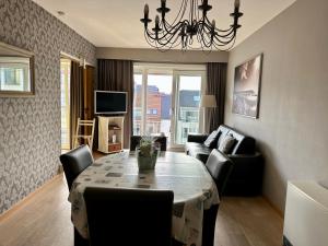 a living room with a table with chairs and a couch at Charming Apartment direct access beach Blankenberge in Blankenberge