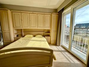 a bedroom with a bed and a large window at Charming Apartment direct access beach Blankenberge in Blankenberge