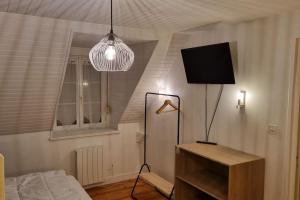 a room with a bed and a television and a lamp at Une petite maison du Rozel - gite tout confort in Le Rozel