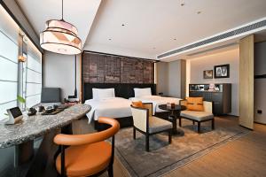 um quarto de hotel com uma cama, uma secretária e cadeiras em Arthur Hotel Luogang Guangzhou em Guangzhou